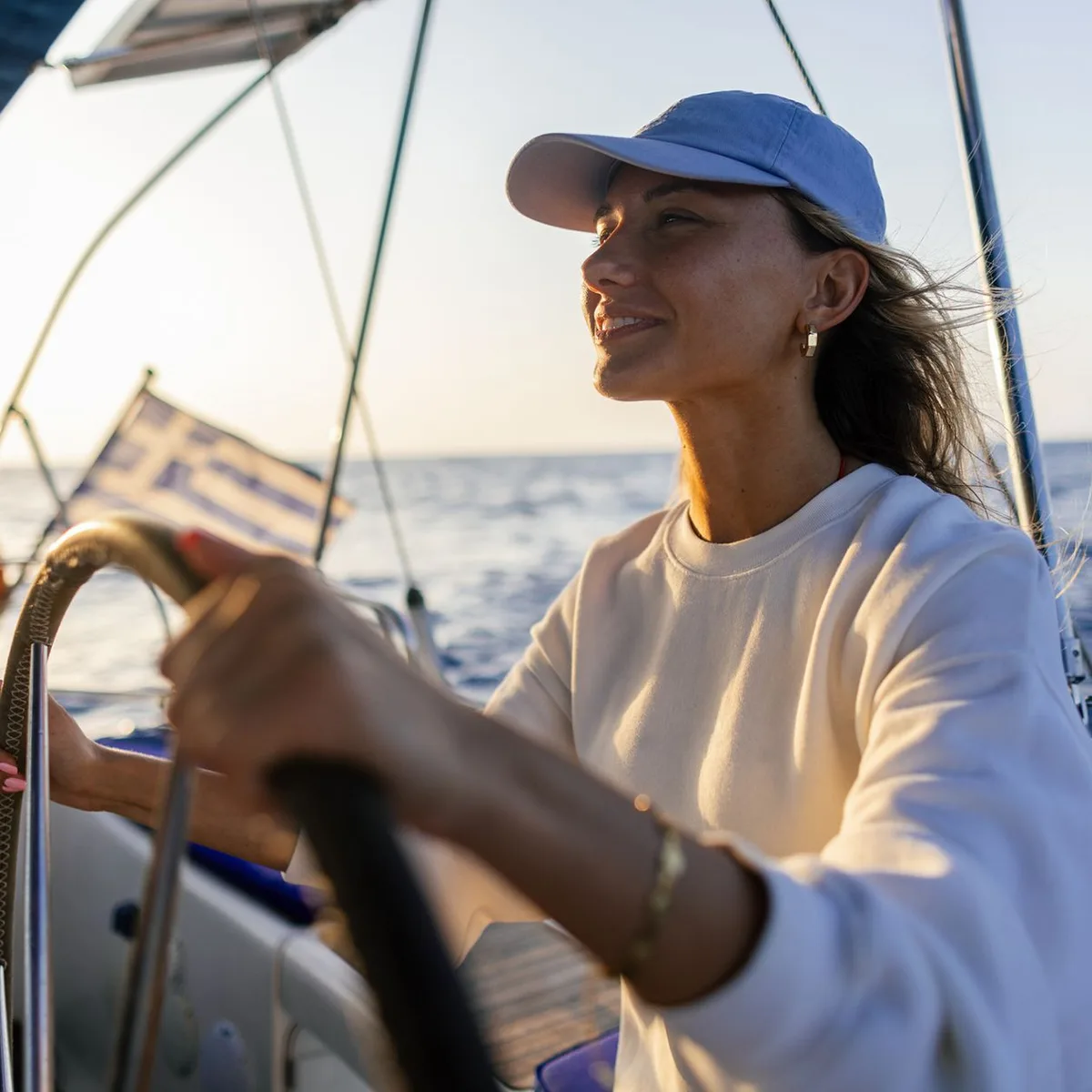 Frau in weiĂem Jackett am Steuerrad eines Segelbootes von 1ayachtcharter Frau in weiĂem Jackett am Steuerrad eines Segelbootes von 1ayachtcharter