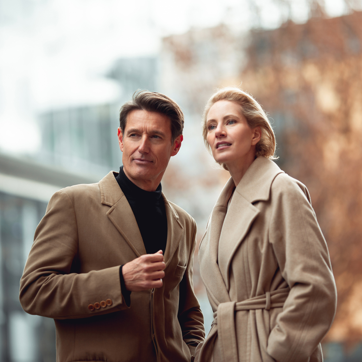 Mann und Frau mittleren Alters, die modern gekleidet durch die Stadt spazieren