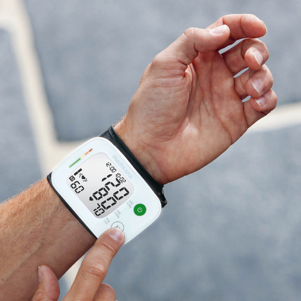 Mann traegt ein Blutdruckmessgeraet an dem Handgelenk