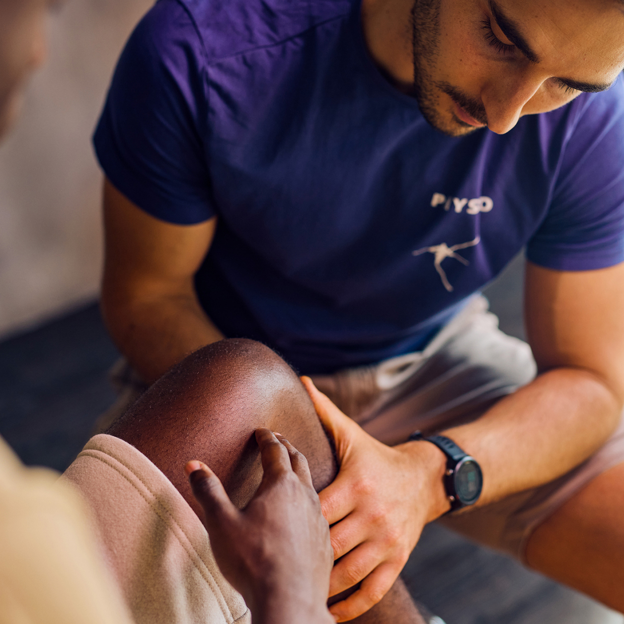 Physiotherapeut untersucht das Knie eines Patienten