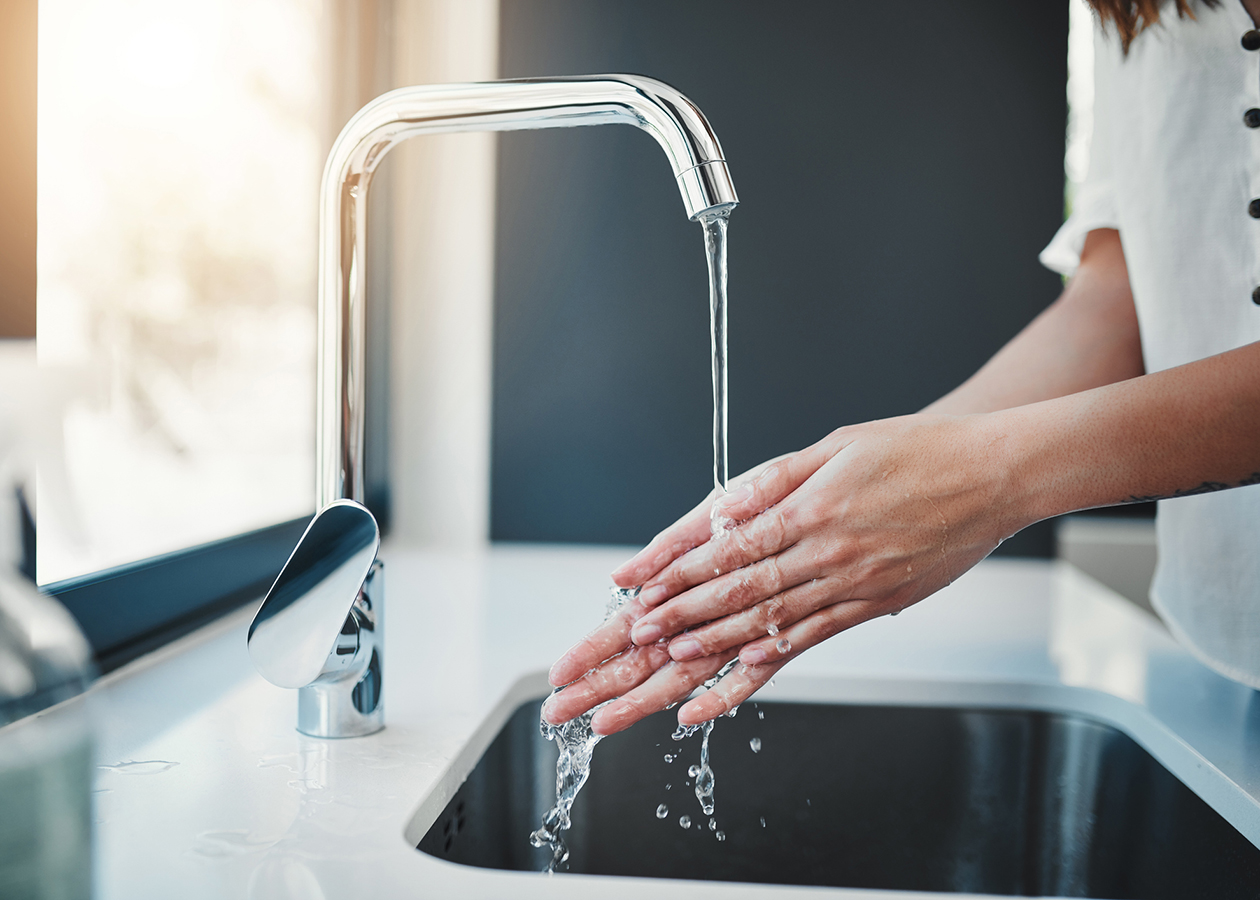 Frau, die sich in der Kuechenspuele die Haende waescht