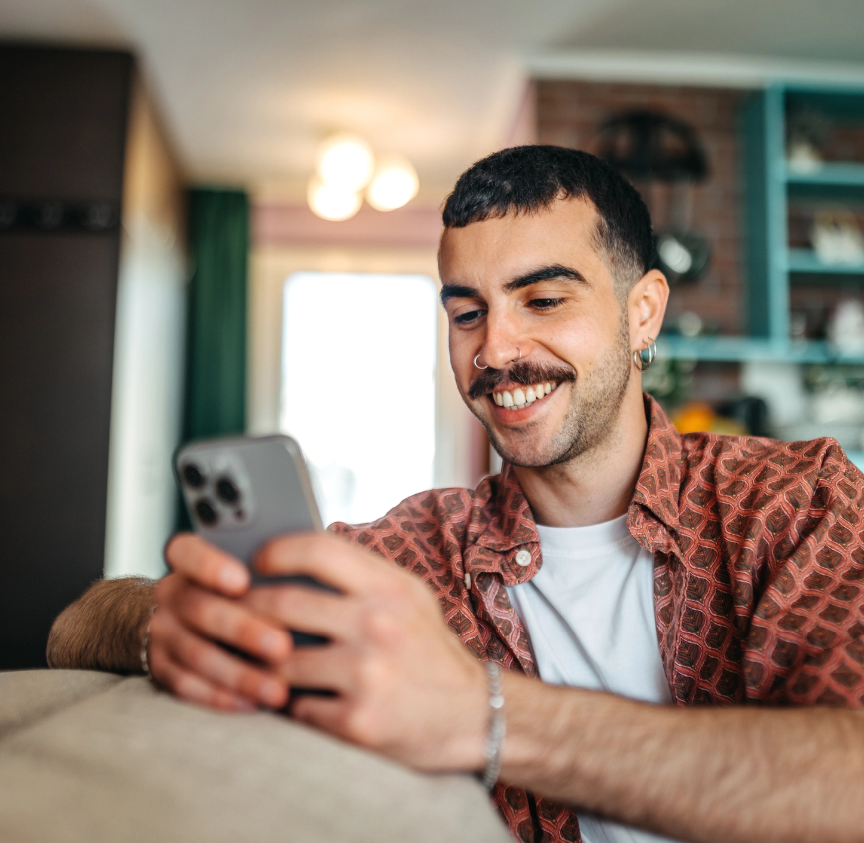 Lächelnde Person nutzt ein Smartphone zu Hause.